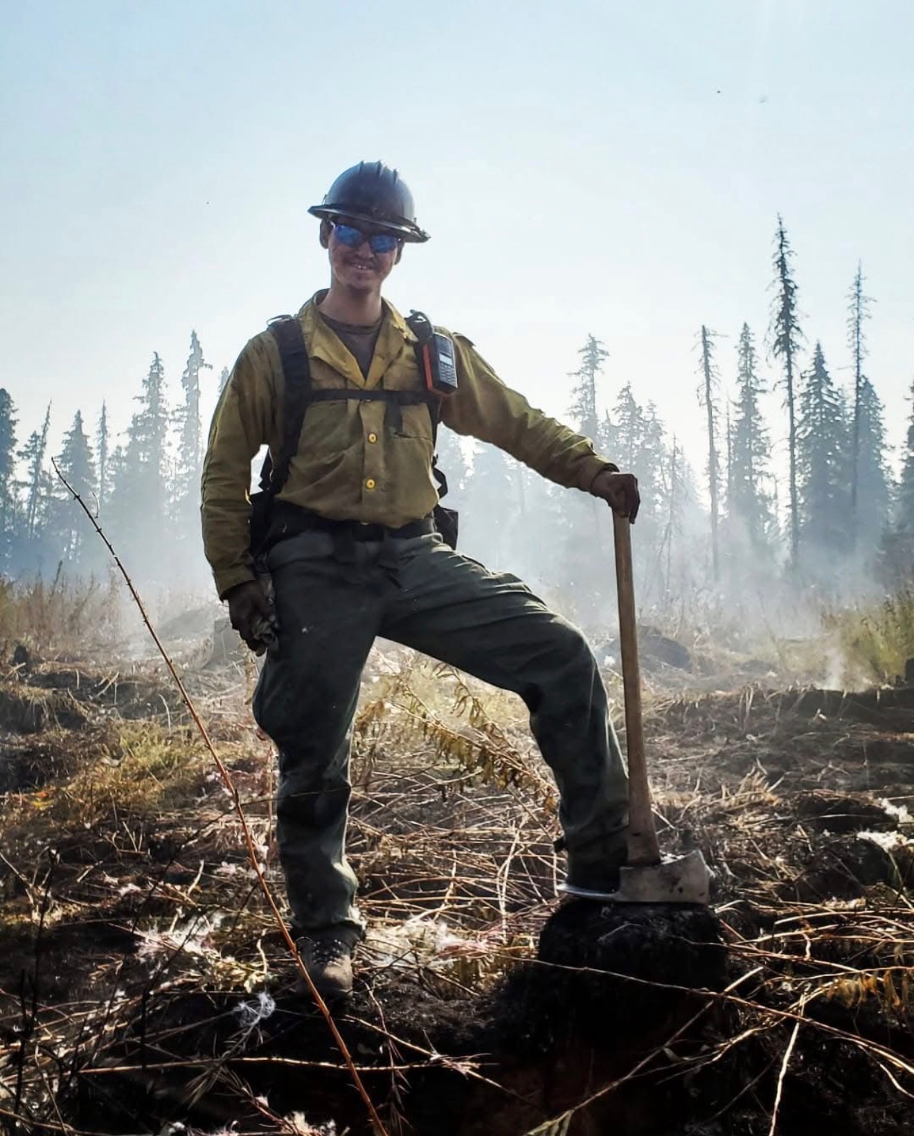 Tom outdoors wearing a hard hat and work gear, holding a hand tool
